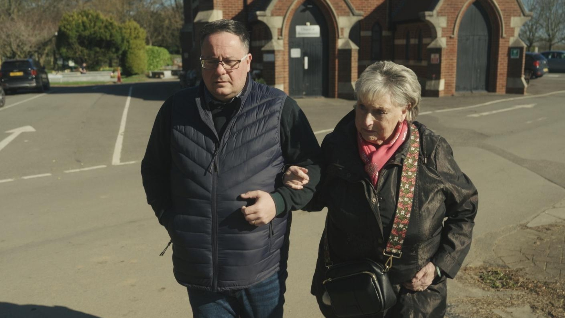 Kevin Hogg and Ann Ming walking arm in arm and looking upset