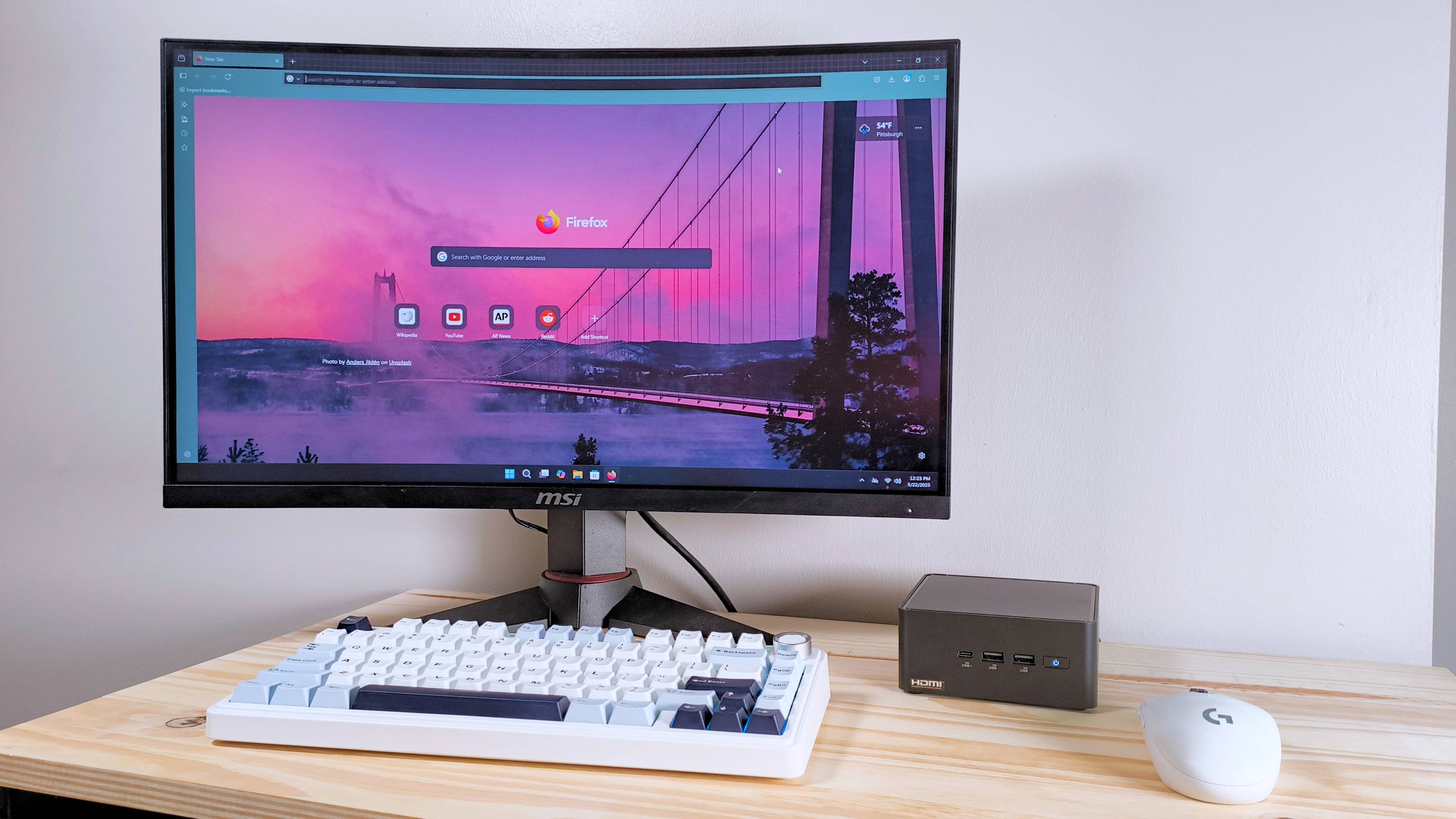 The ASUS Nuc 14 Pro on a table with a monitor, keyboard, and mouse
