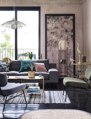 pink living room with grey sofa and chair, black floor, gold coffee table, bar trolley, pendant light, stripe rug