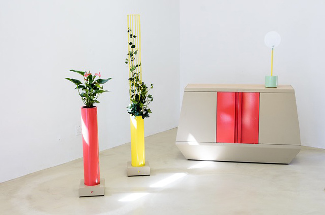 Red and yellow plant pot with flowers in stood next to a beige and red cabinet