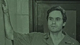 Ted Bundy leaning on a wall in a prison jumpsuit