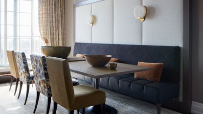 Large dining room space with cozy, navy, fabric bench seating and chairs across long wooden table