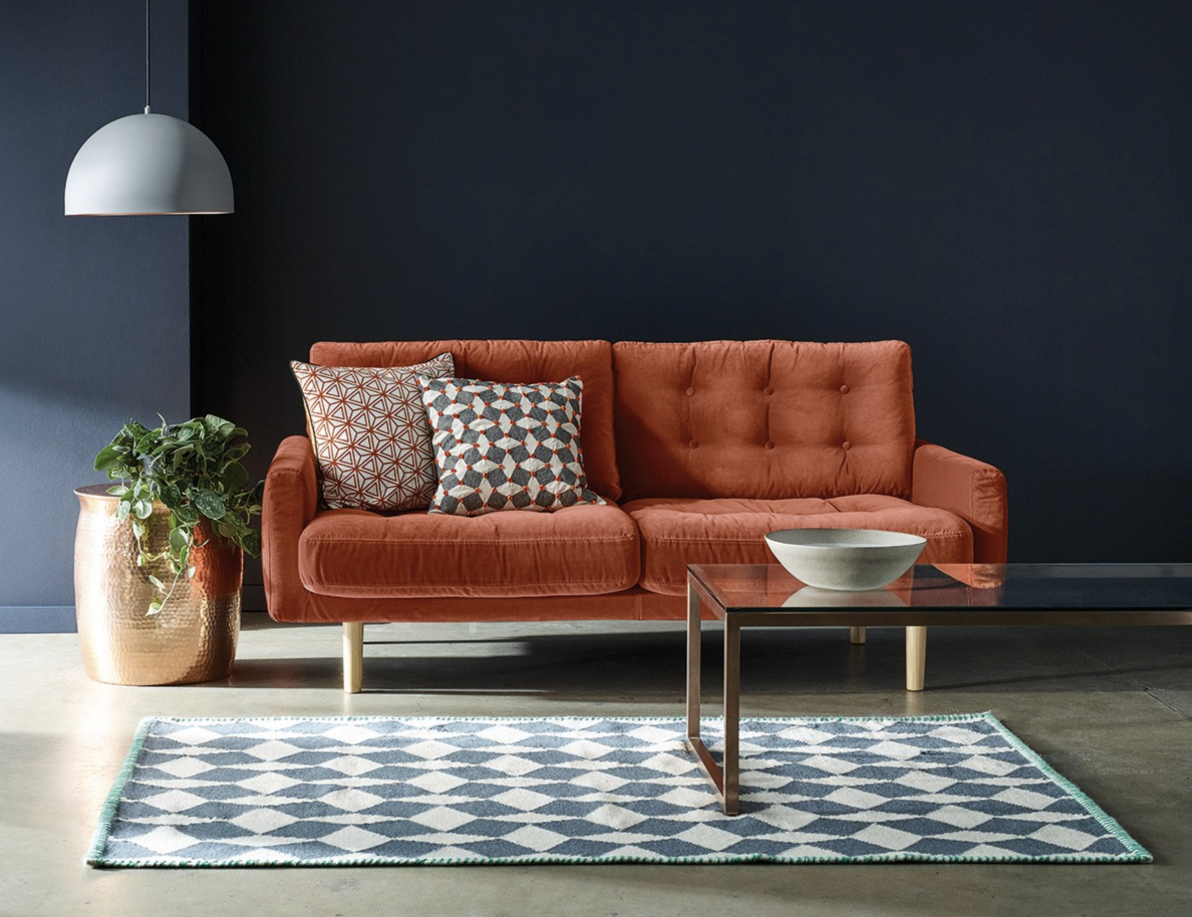 Habitat Fenner 3 Seater Sofa in a dark blue living space with a wooden floor, glass coffee table, bronze planter and a white hanging lamp