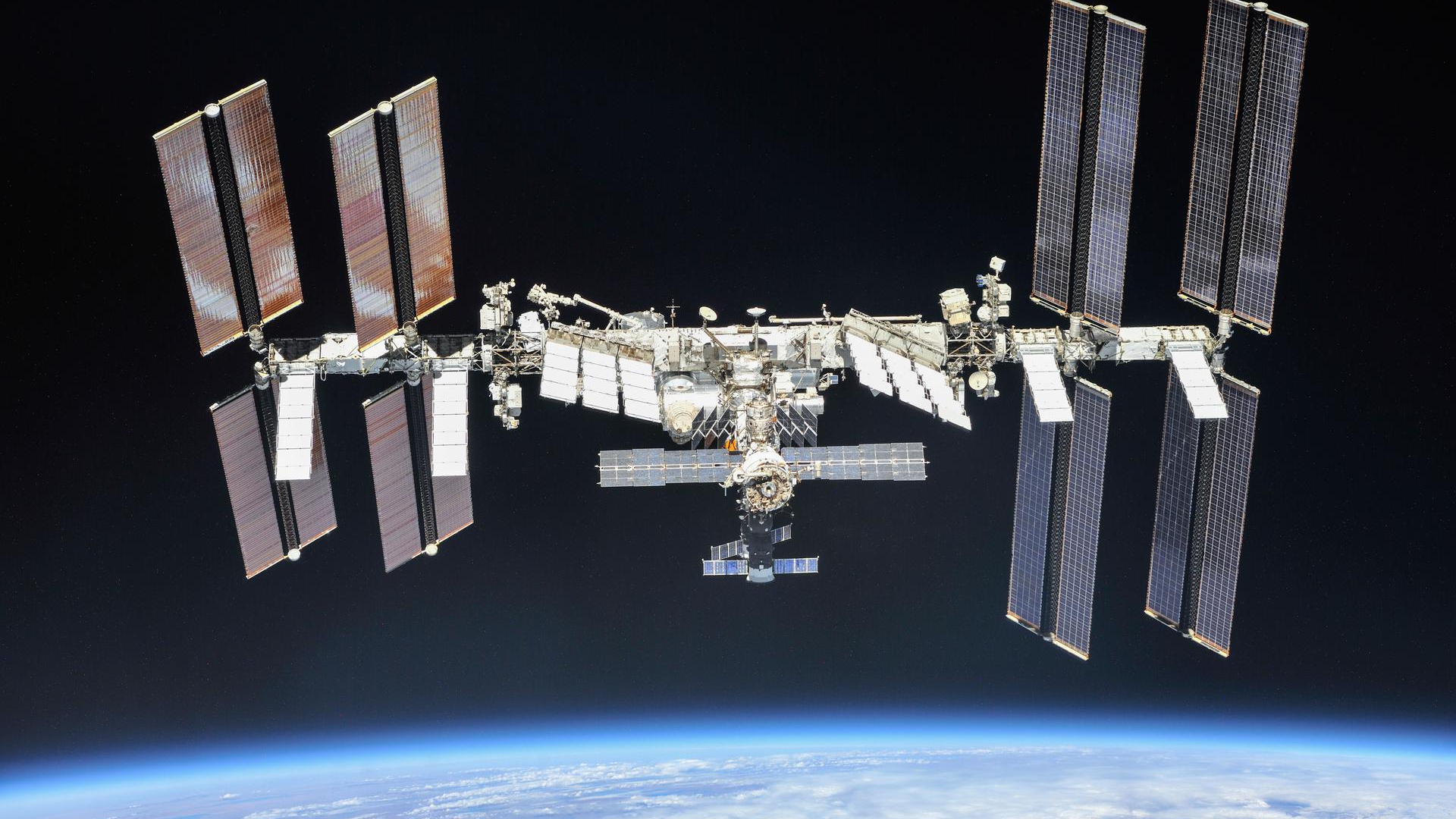 photo of the international space station taken in orbit, with the curve of earth visible against the blackness of space