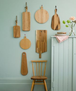 kitchen area with grey wall and wooden chopping boards on wall with chair