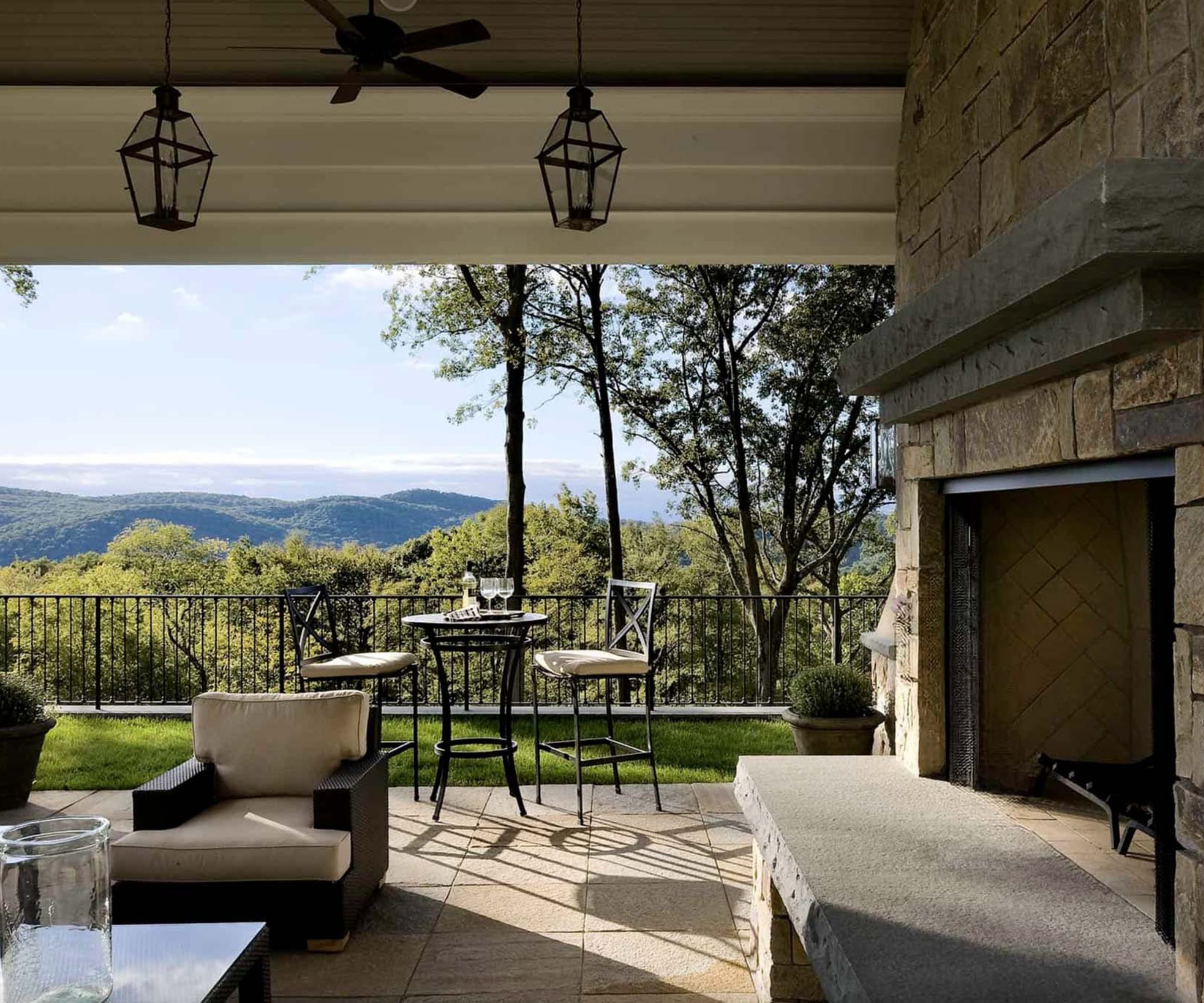 Outdoor terrace with fireplace and metal chairs overlooking mountain views