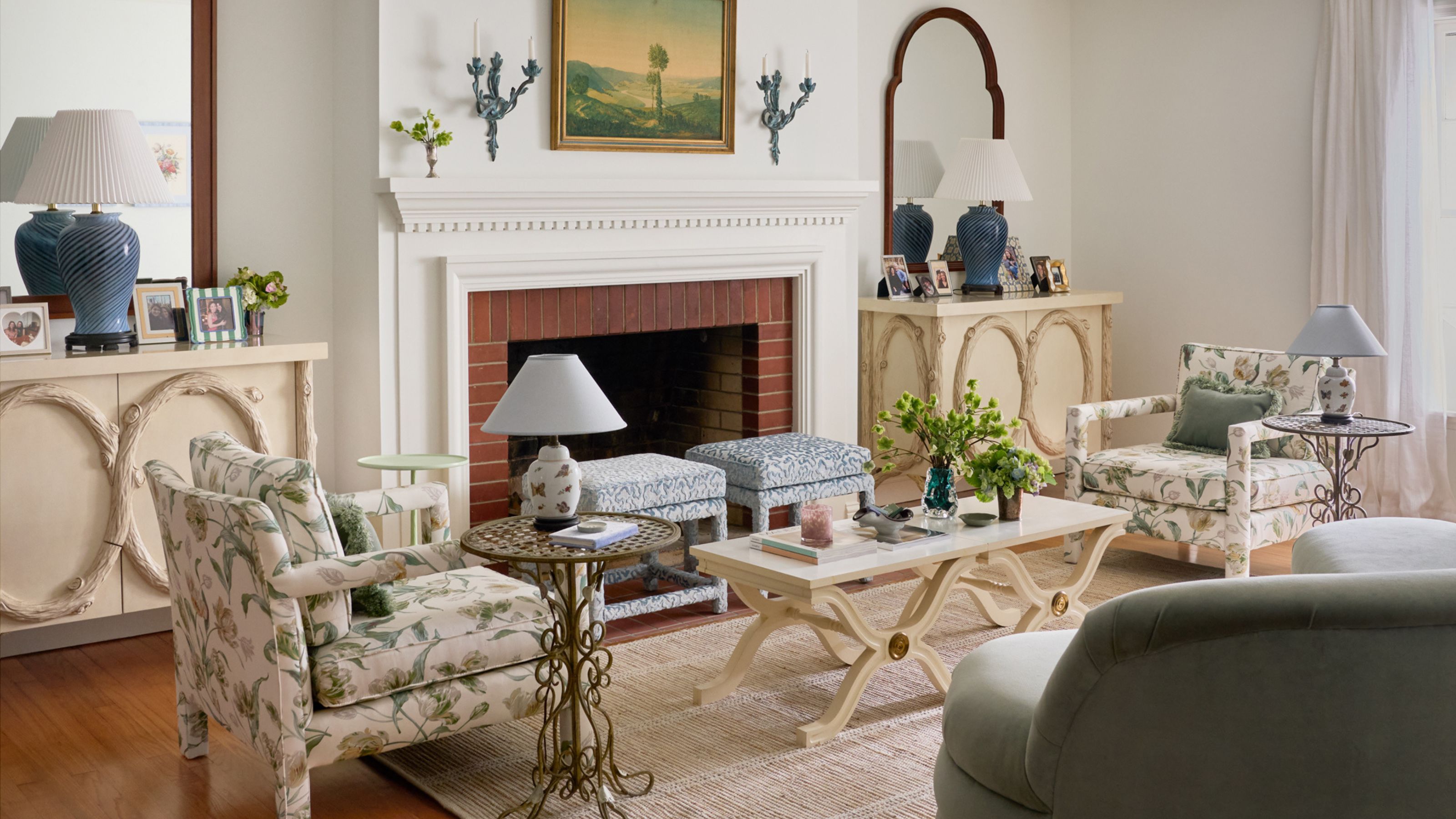 a white painted living room with original fireplace layered with sculptural furniture, floral chairs and decorative details