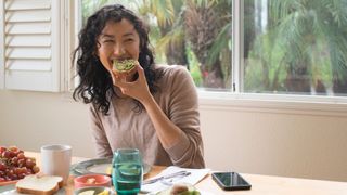 Woman eating breakfast of toast and avocado, part of the 16:8 diet