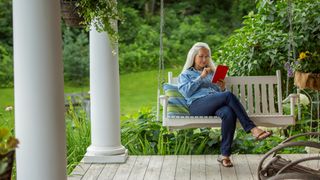 Senior woman reads on porch, aging in place successfully