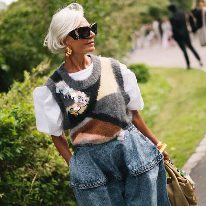 grece ghanem wears sunglasses, a knitted vest and jeans