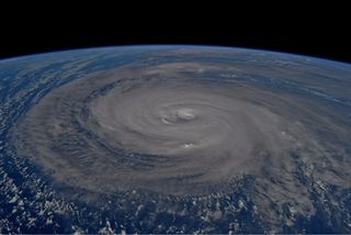 Dark typhoon swirls across the blue arch of Earth's Pacific Ocean.