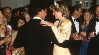 WELLINGTON, NEW ZEALAND - APRIL 21: Prince Charles, Prince of Wales and Diana, Princess Of Wales, wearing a yellow satin ballgown designed by Murray Arbeid with the Queen Mary Cambridge Lover's Knot Tiara, pearl drop earrings and a heart shaped diamond necklace which was a gift from Prince Charles after the birth of Prince William, dance together during the Government House Ball on April 21, 1983 in Wellington, New Zealand.