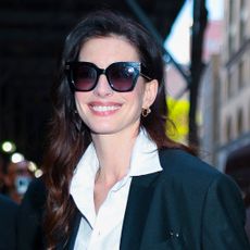 Anne Hathaway wearing a black versace suit as she walks into a hotel