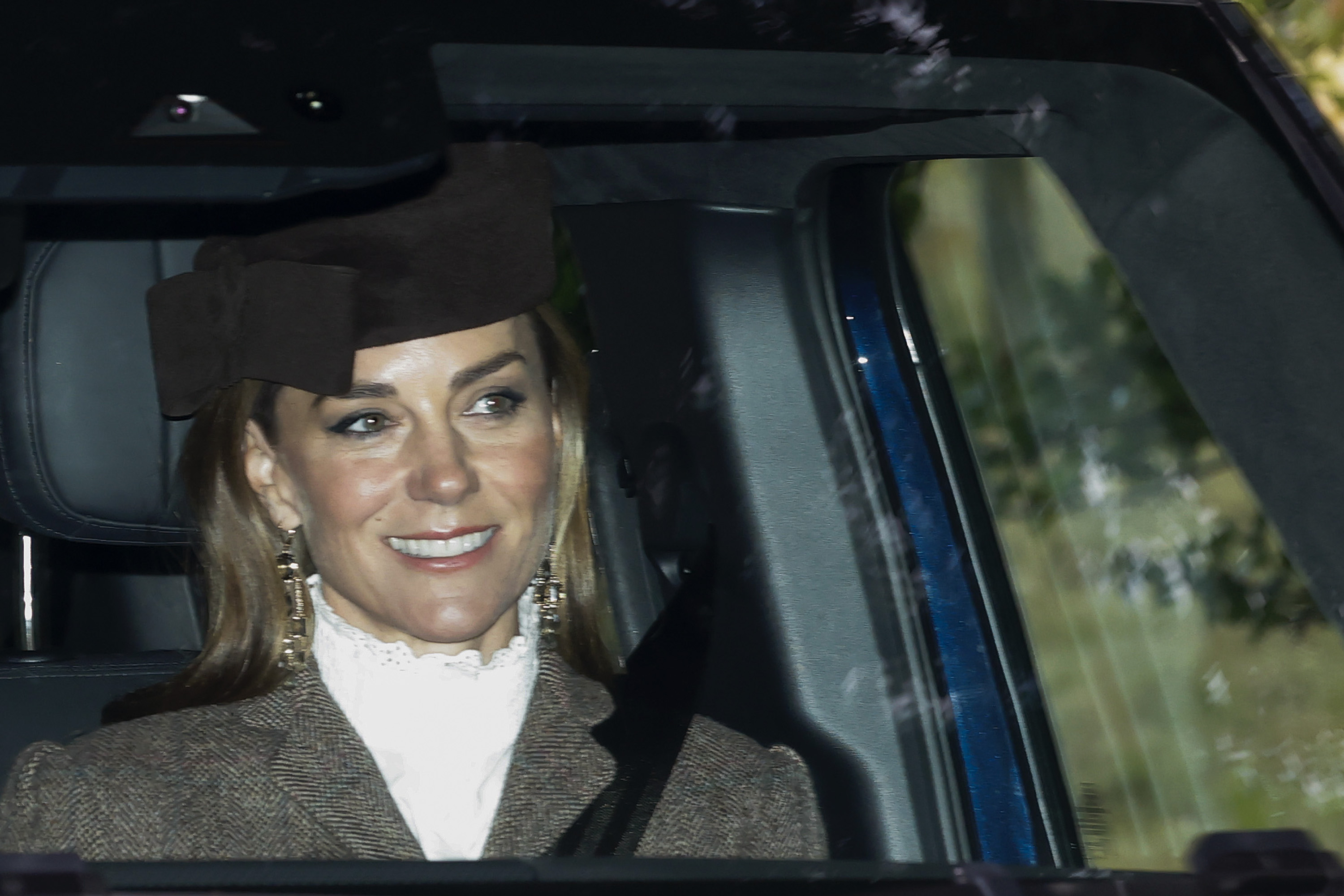 Princess Kate riding in a car with a white blouse