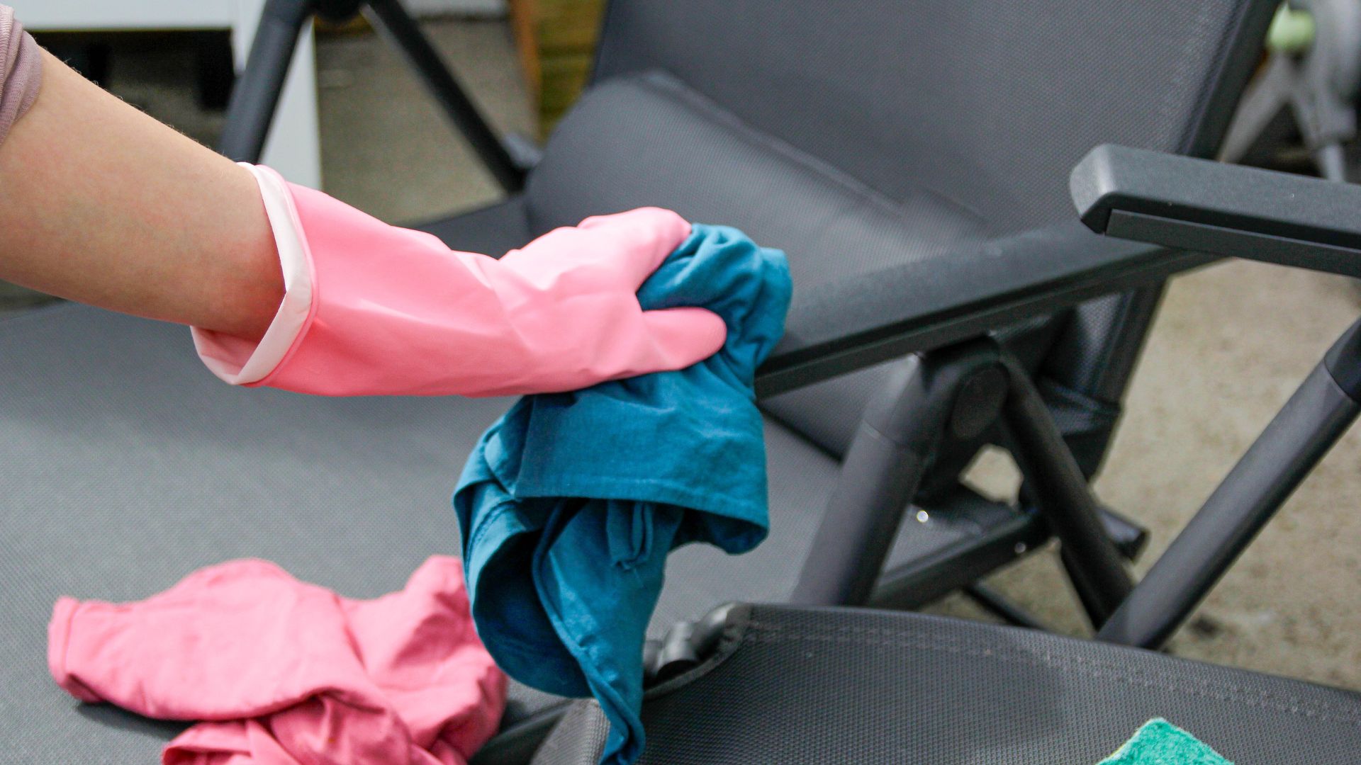 picture of woman cleaning outdoor furniture with rag and gloves on