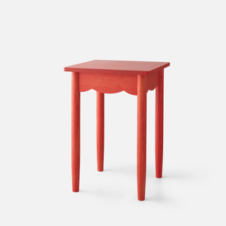 red wooden bedside table with scalloped edge