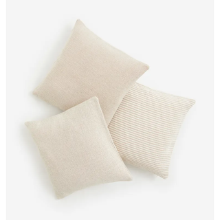 three beige square pillows with different striped patterns