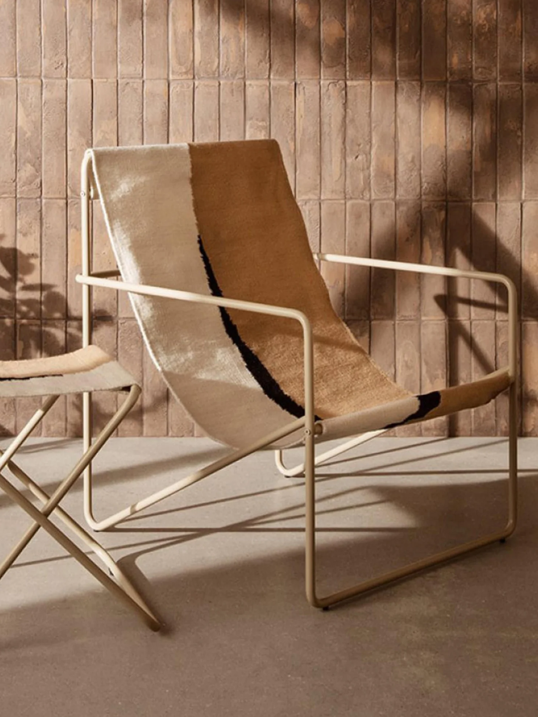 An outdoor chair with a beige metal frame and an off-white and brown fabric