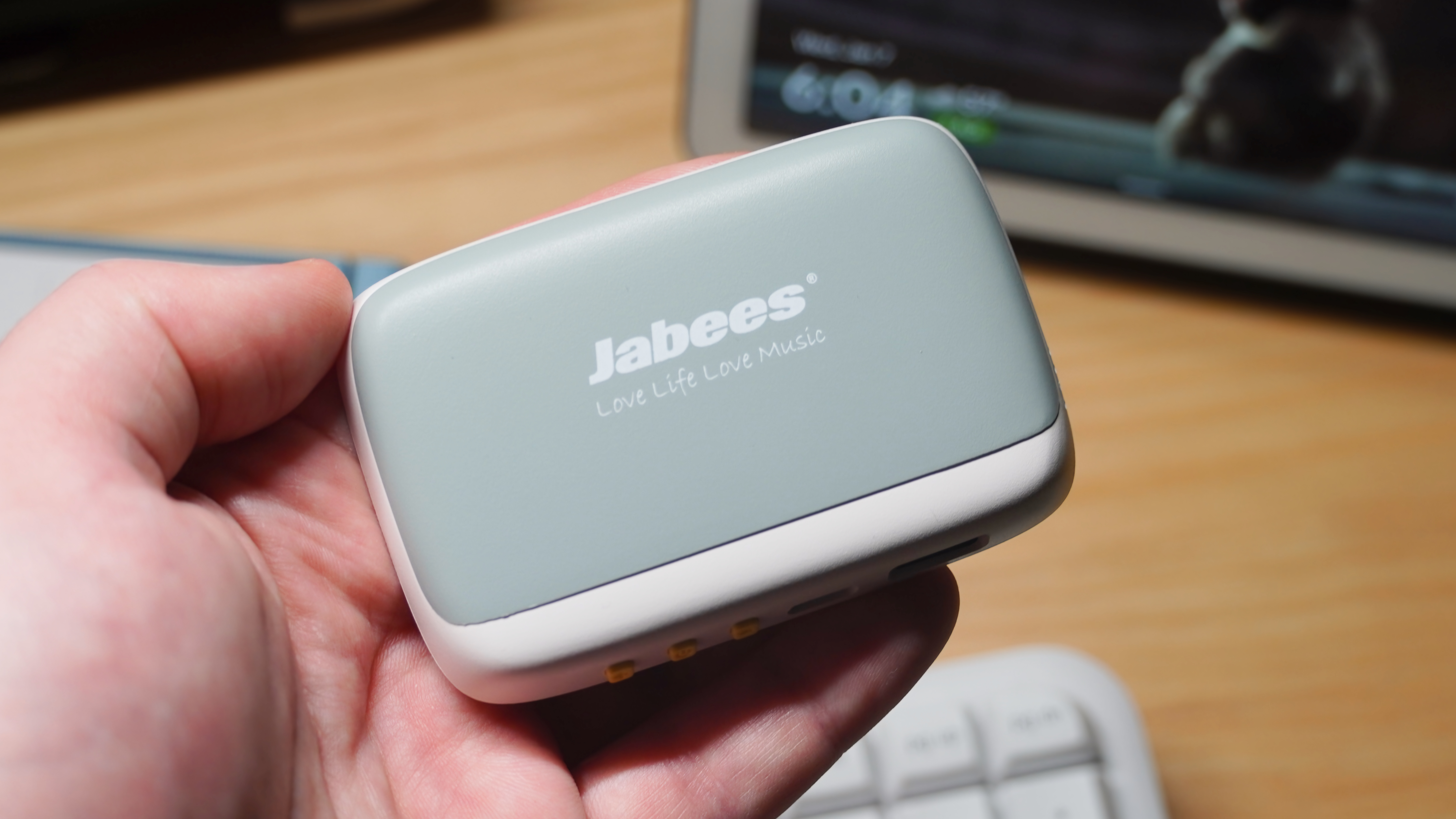 The Jabees Peace Pillow Speaker in the hand and on a pillow.