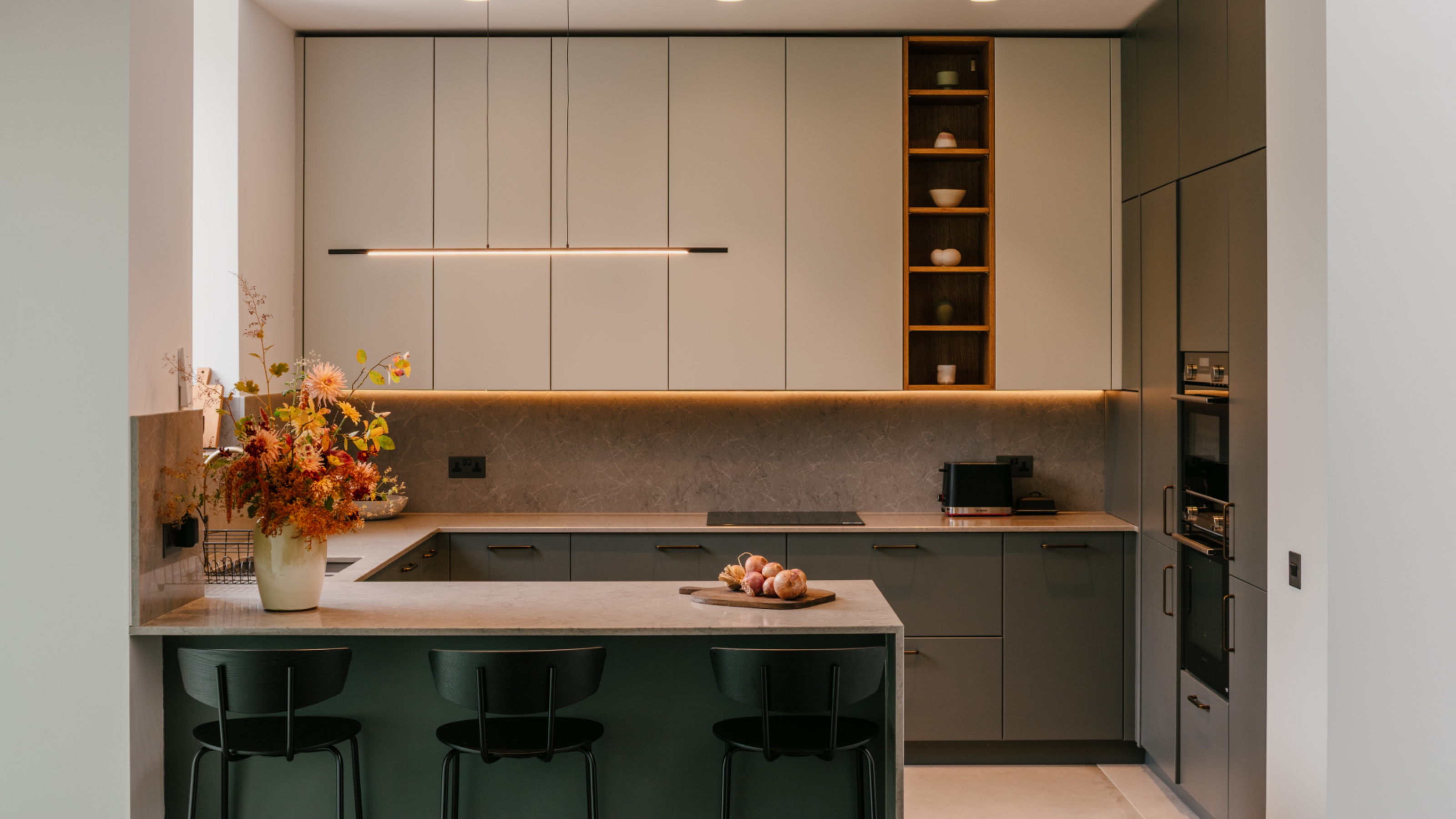 modern kitchen with U-shaped layout, wall units, in built ovens, pale worktop