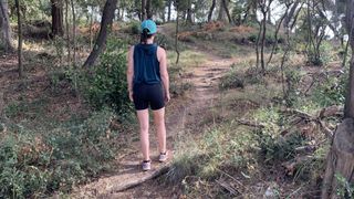 Woman from back hiking on forest trail