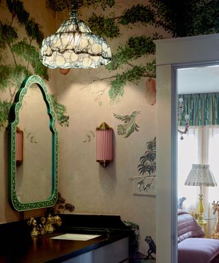 Vintage style bathroom with green mirror and pink wallpaper and botanical mural