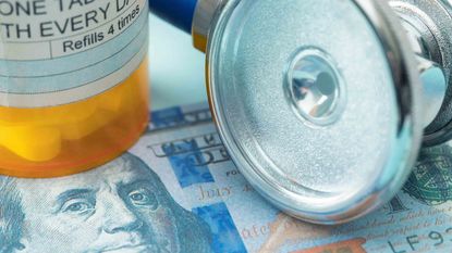 Pill bottle and stethoscope laying on $100 bill 