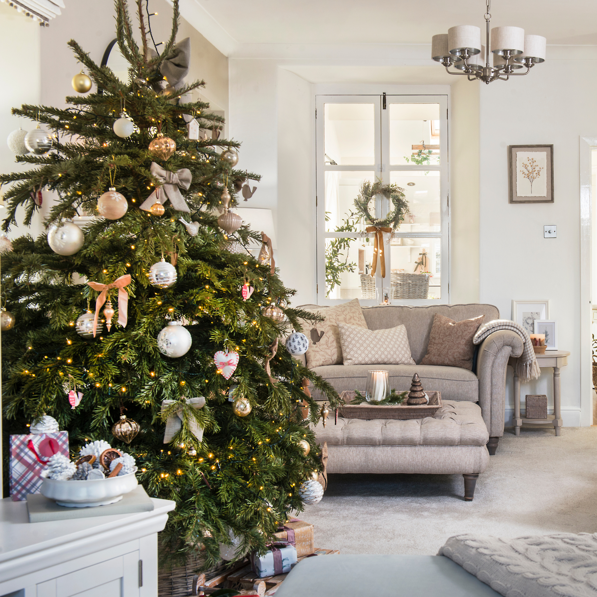Real Christmas tree decorated in a neutral living room.