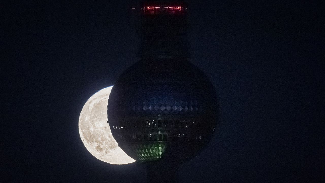 The rising full moon is pictured behind the Berlin TV tower on October 09, 2022 in Berlin, Germany.