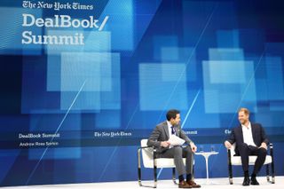 Prince Harry sitting on stage at the NYTimes Dealbook summit in a blue suit