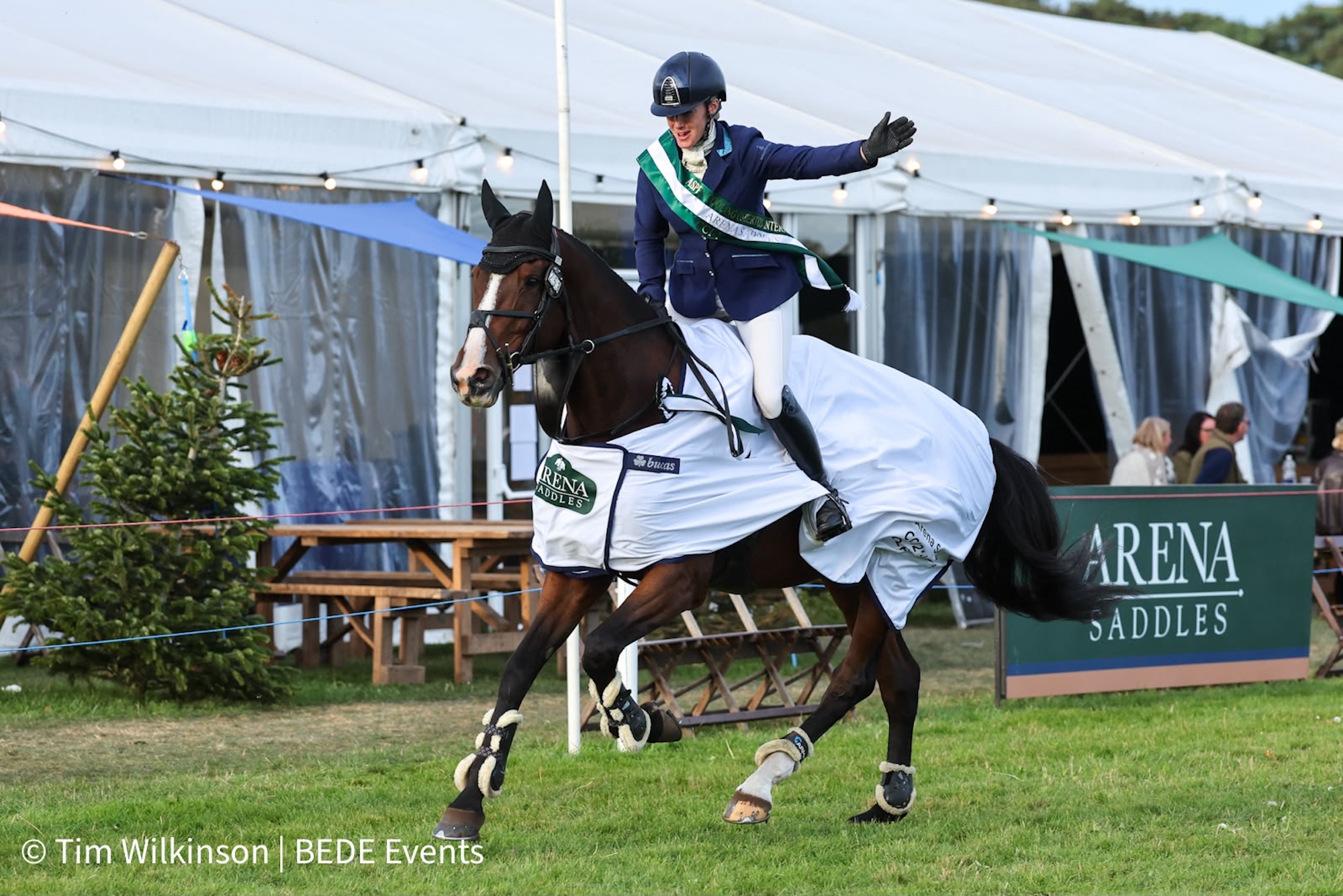 Image shows Imogen King riding a bay horse, who is wearing a winner's rug, on a lap of honour at Osberton.