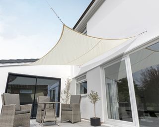 A small white shade sail attached to the side of a house