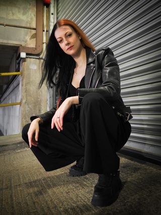 Portrait of a person squatting in an industrial setting, taken on the OM System OM-3 with the OM System M.Zuiko 17mm f/1.8 II