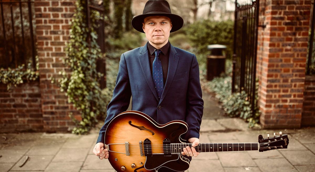 Artie Zaitz is suited and booted and holds a sunburst Gibson ES-330T hollowbody.