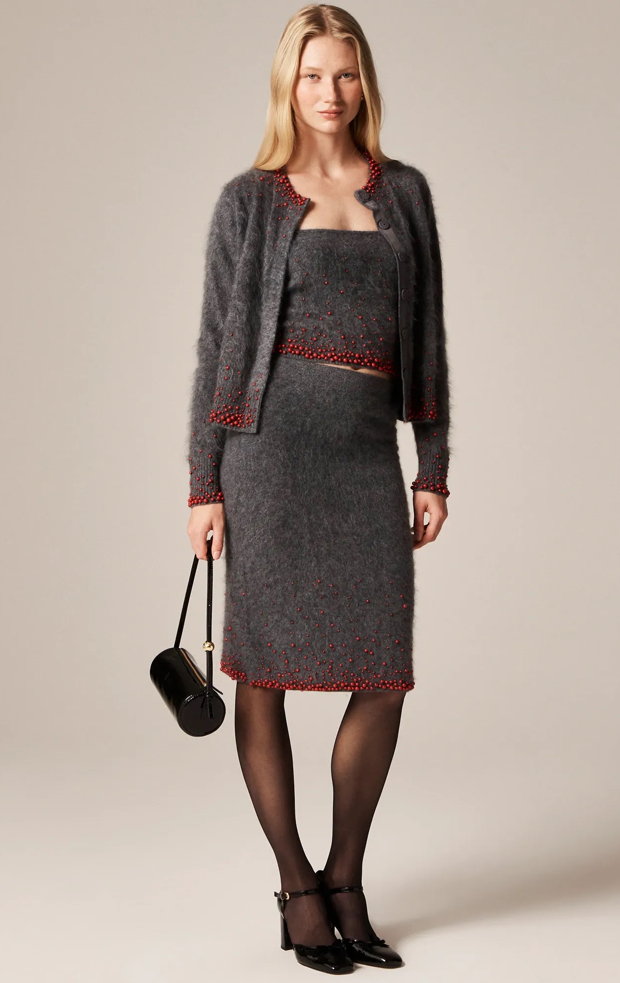 A model wearing a gray brushed cashmere midi skirt with beaded embellishments and a matching tank top and cardigan.