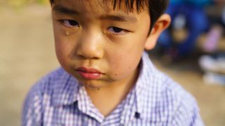 photo of a young boy making a pouty face a few tears roll down his cheeks