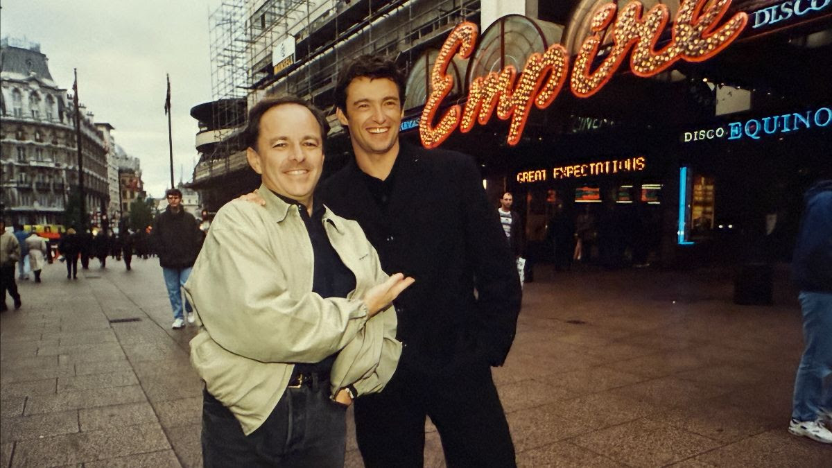 Two men (Brian Walsh and Hugh Jackman) standing with city background