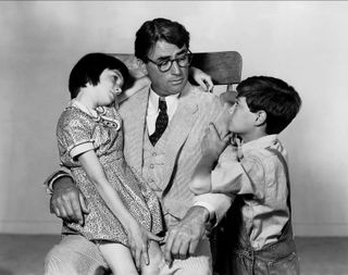 atticus finch embraces his children in a black and white still from To Kill a Mockingbird