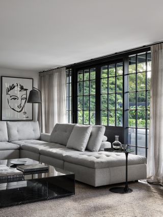 gray and black living room with grey sectional, artwork, black marble coffee table, side table, textured neutral rug