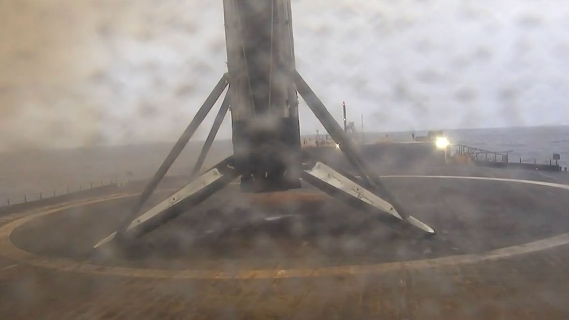 a spent stage of a rocket stands on its landing legs atop a sea-based platform after returning from space.