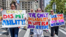 Participants at the Disability Pride parade in New York City holding up signs while marching from Madison Square Park to Union Square Park.