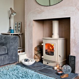 A pink living room with plastered walls and a log burner