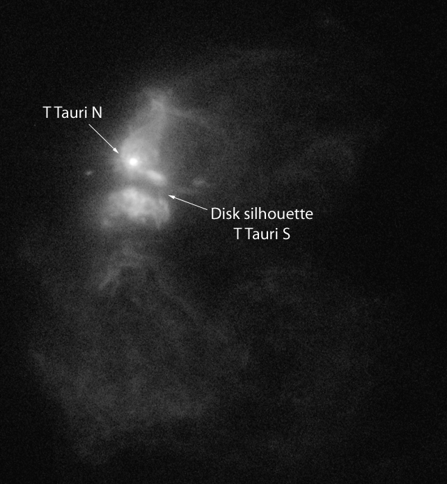 two bright stars, one white and one red, seen ins pace in a cloud of dust. many other smaller, fainter stars can be seen in the background