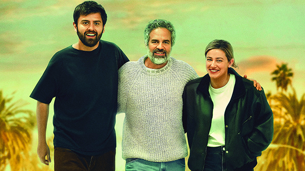 Hal (Cooper Raiff), Dad (Mark Ruffalo) and Harper (Lili Reinhart) smiling at the camera with their arms around each other.
