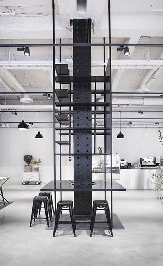 Vertical beam painted black with a table and stools around it