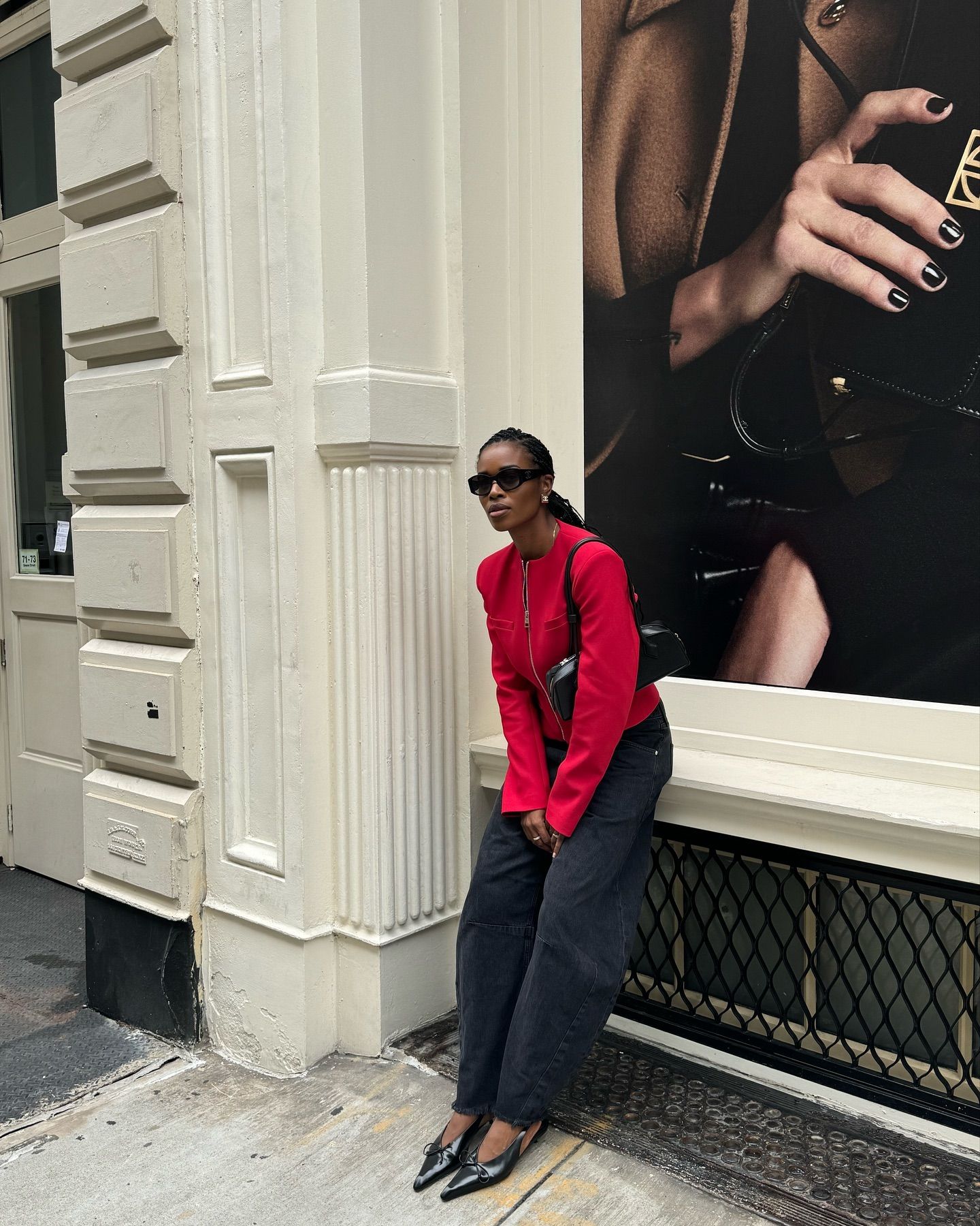 @nlmarilyn wears a red jacket with dark barrel leg jeans and pointed toe heels
