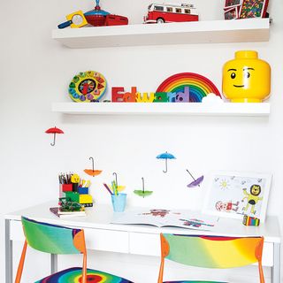 kids room with white walls, shelving and desk with colourful chairs and accessories