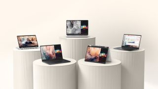 5 Dell Pro laptops on white cylindrical stands