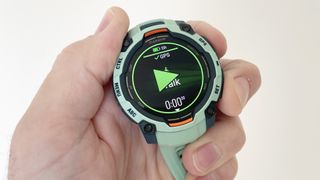 The Garmin instinct 3 in a user's hand showing GPS actively tracking a walk