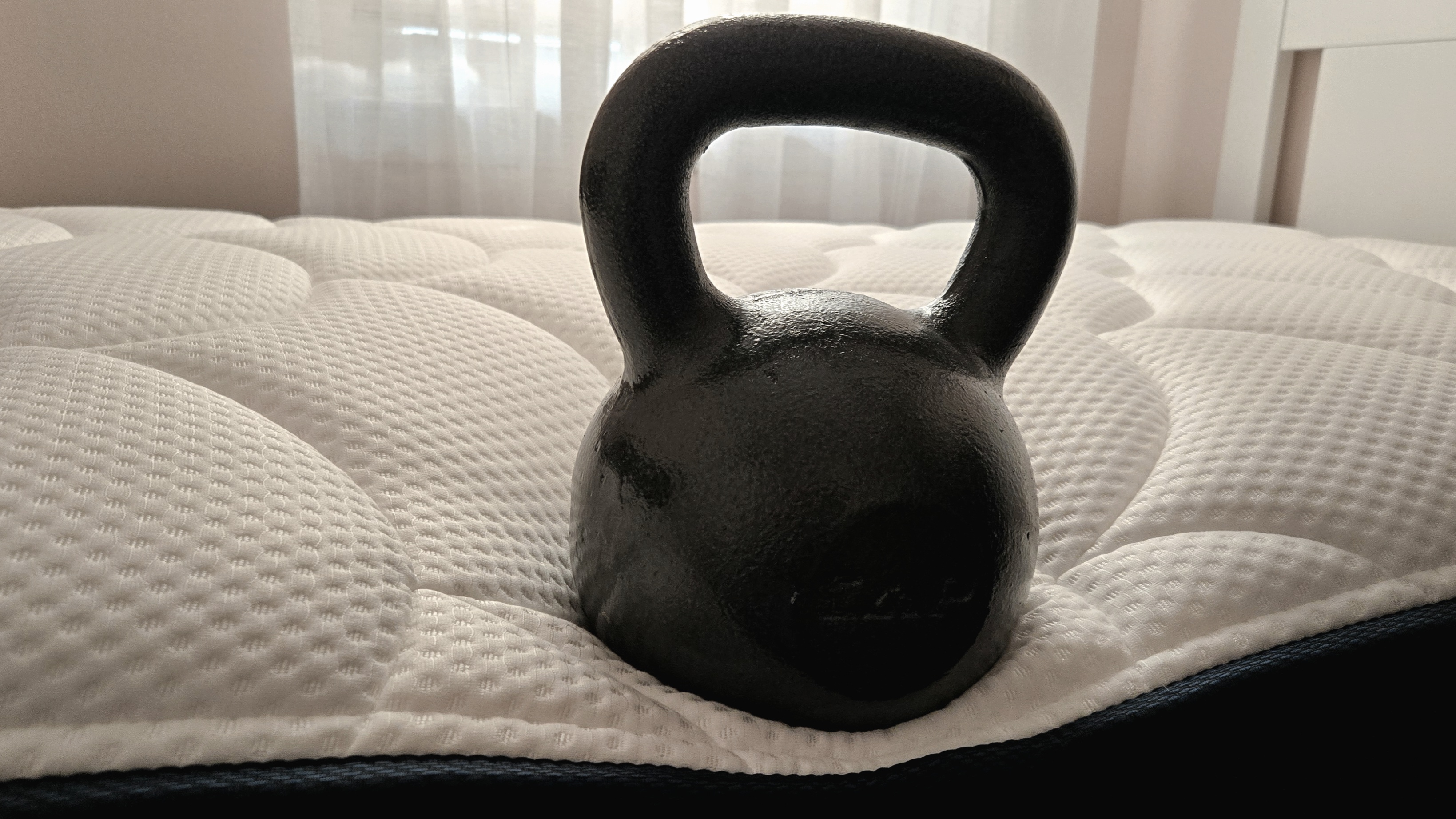 Testing edge support for the DreamCloud Classic Memory Foam Mattress review by placing a 50lb kettlebell at the center perimeter